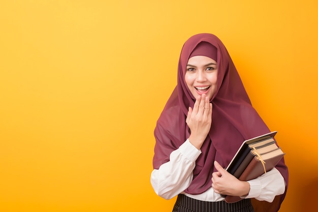 Beautiful University student with hijab on yellow wall