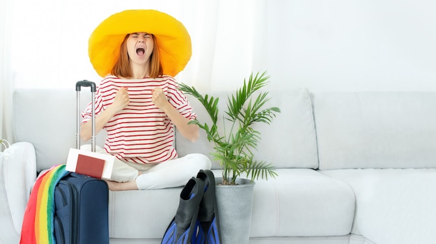 Beautiful upset girl in a yellow hat stays at home and plans a trip on vacation.Waiting for travel.