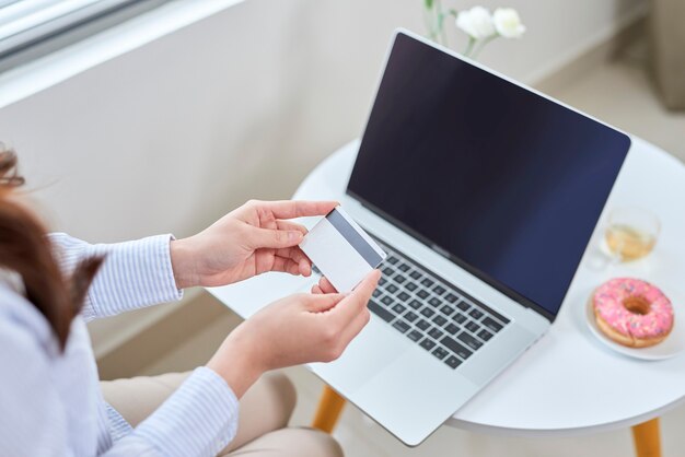 A beautiful using laptop and her bank card while shopping from home without living sofa