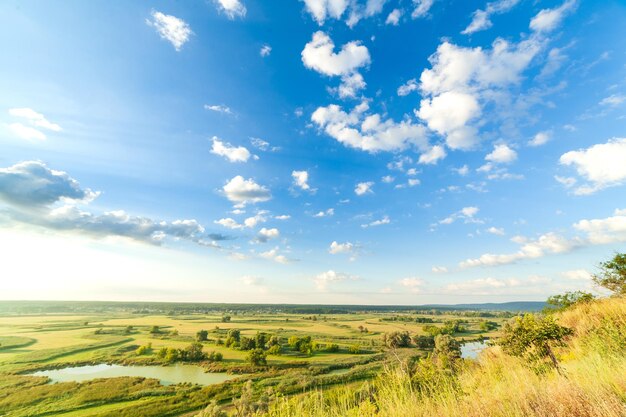 A beautiful valley with a river blue sky with large clouds and bright sun Aerial 4K UHD