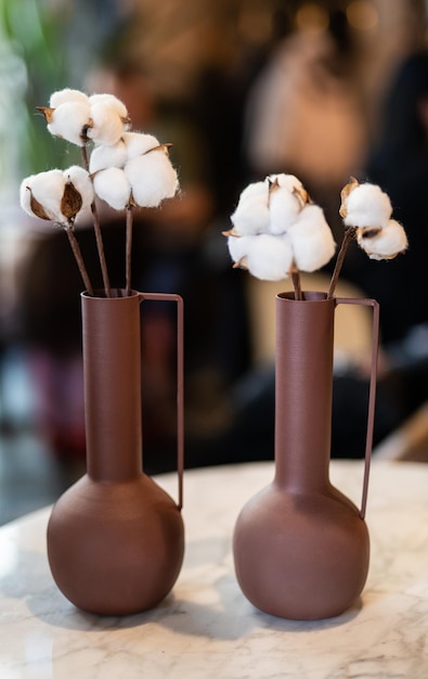 Beautiful vase with cotton flowers on the table