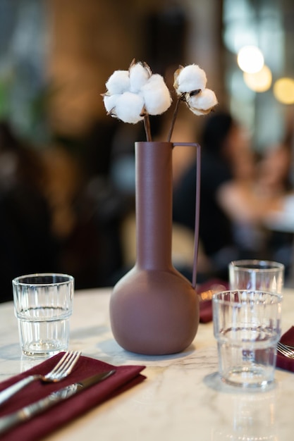 Beautiful vase with cotton flowers on the table