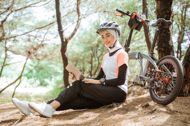 Beautiful veiled woman using digital tablet while sitting