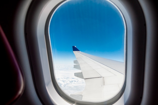 飛行機の窓を通して見えるCloudscapeと飛行機の翼の美しい景色