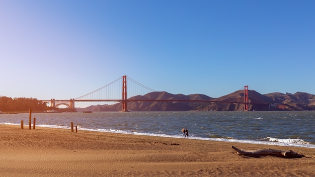 석양에 비추어 유명한 골든 게이트 브리지의 Crissy Field 해변에서 아름다운 전망