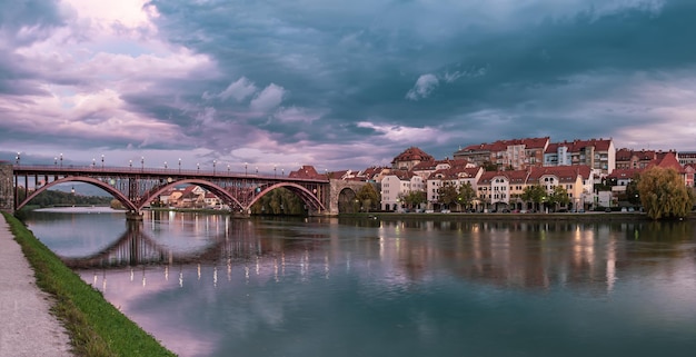 Beautiful view of Maribor city, Slovenia, at sunrise, with river and dramatic sky. Travel outdoor landscape panorama.