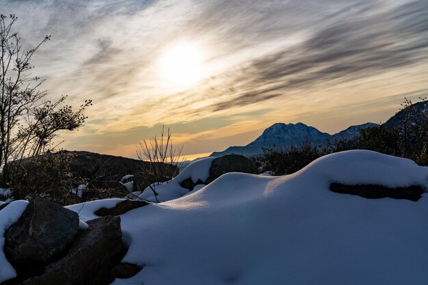 雲の後ろに太陽とラカンパーナと曇りの日の雪の山の美しい景色