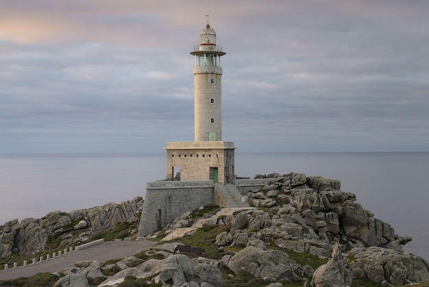 Beautiful view of a Punta Nariga Lighthouse on a coastal cliff during sunrise in Galicia, Spain