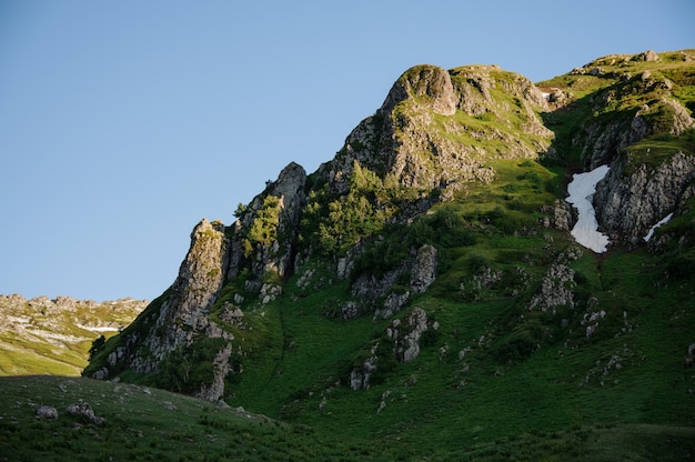 雪の残骸と草で岩が多い丘の美しい景色