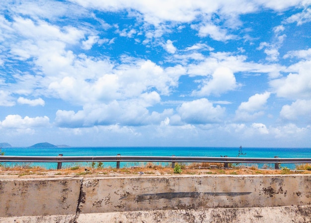 晴れた夏の日の海の美しい景色と青い曇り空のクローズアップコンクリートの道路障壁車の旅行旅行のコンセプトの背景