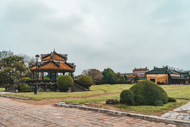 베트남 후에(Hue)의 여름 화창한 날 임페리얼 시티(Imperial City) 정원의 푸른 하늘 배경에 있는 전통 베트남 파빌리온의 아름다운 전망. 후에는 아시아의 인기 있는 관광지입니다.