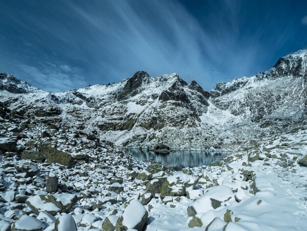 Foto splendida vista con alte rocce con cime innevate e il lago glaciale negli alti tatra