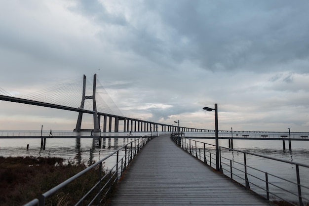 흐린 날씨에 긴 바스크 다 가마 다리(Vasque da Gama Bridge)의 목조 부두의 아름다운 전망 포르투갈 리스본 여행