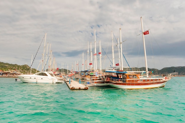 Beautiful views of the marina yacht with masts on the background of the mountains under a cloudy sky