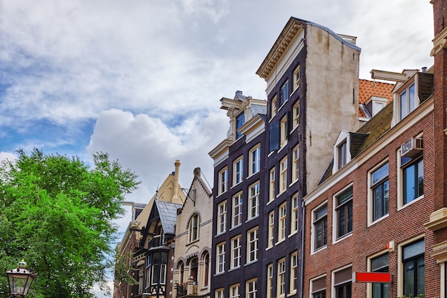 アムステルダムの古代の建物の人々の堤防の通りの美しい景色