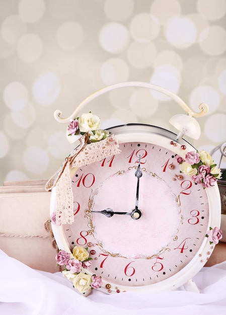 Photo beautiful vintage alarm clock with flowers on light background