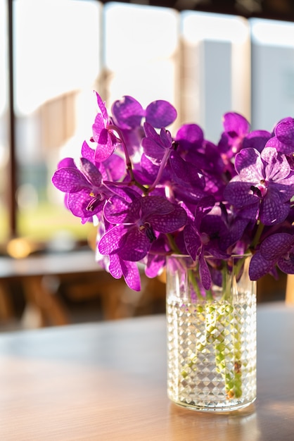 Beautiful violet orchids vase on wood table in restautant