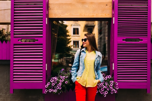 Beautiful violet window with shutters and flowers and woman posing