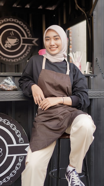 Beautiful waitress in apron looks cool sitting in cafe booth container