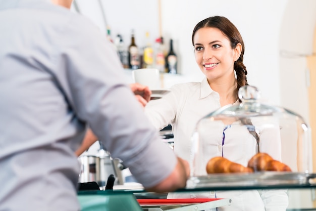 Beautiful waitress serving male customer with a cup of coffee fo