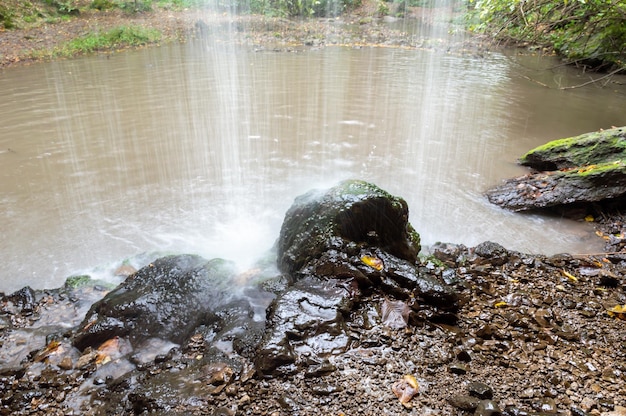 A beautiful waterfall pours on black stones and into the lake