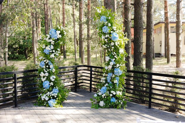 屋外の花で飾られた森の美しい結婚式のアーチ