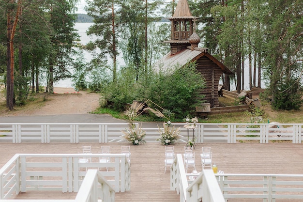 写真 湖と古い教会の背景に美しい結婚式のアーチ
