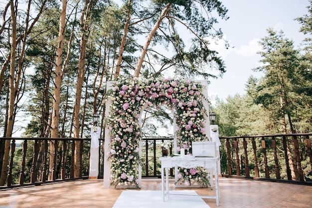 Beautiful wedding arch for the wedding ceremony decorated with fresh flowers in a pine forestx9