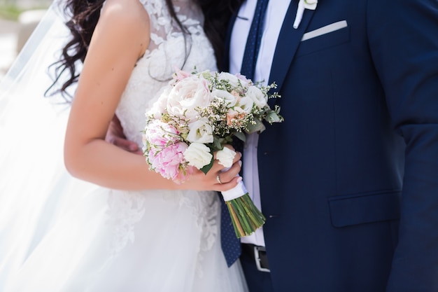 Beautiful wedding bouquet of different flowers in the hands of the bride