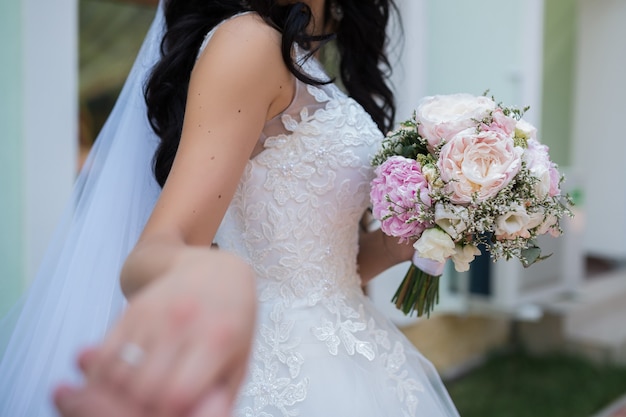 Beautiful wedding bouquet of different flowers in the hands of the bride