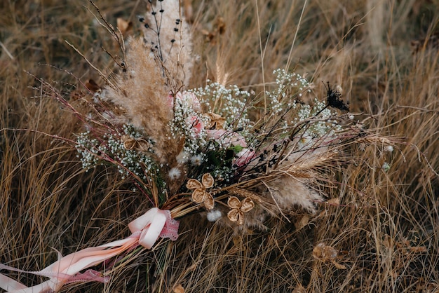 Photo beautiful wedding bouquet on the dry grass on an autumn day.