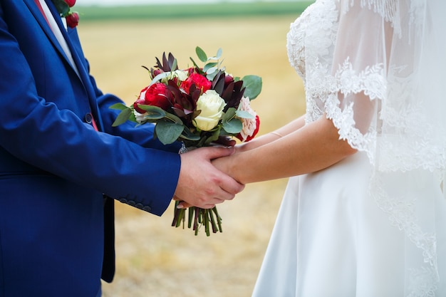 Beautiful wedding bouquet of flowers in the hands of the newlyweds