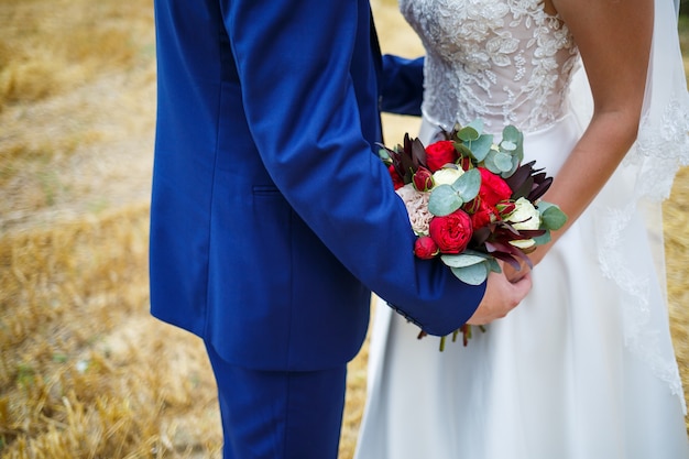 Beautiful wedding bouquet of flowers in the hands of the newlyweds