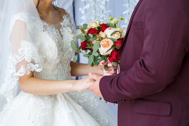 Beautiful wedding bouquet of flowers in the hands of the newlyweds