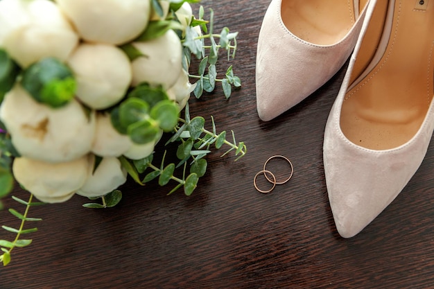 Bellissimo bouquet da sposa di anelli di fiori scarpe da sposa su fondo di legno. dichiarazione d'amore, primavera. partecipazione di nozze, auguri di san valentino. fedi nuziali. dettagli del giorno del matrimonio.