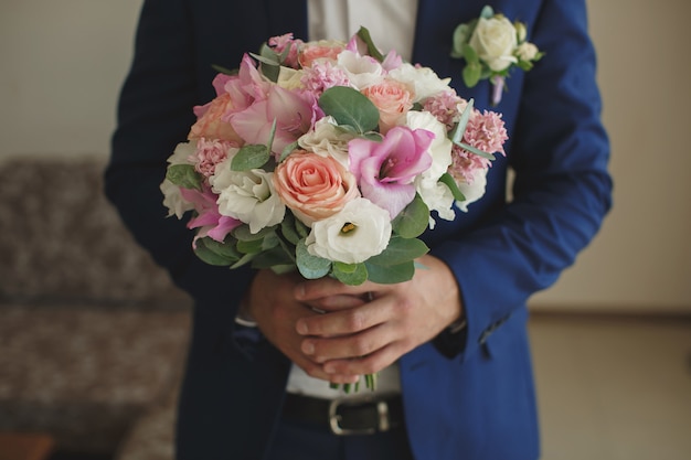 Beautiful wedding bouquet in hands of the groom