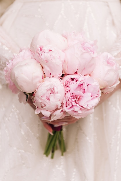 Beautiful wedding bouquet of pink peonies in the hands of the bride