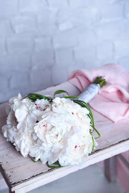 Beautiful wedding bouquet on wooden ladder on light wall background