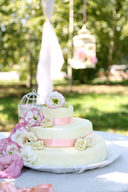 Beautiful wedding cake with flowers on table outdoors