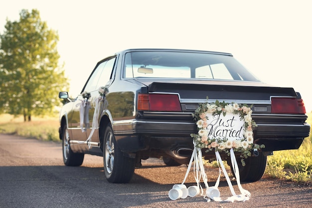 Photo beautiful wedding car with plate just married and cans outdoors