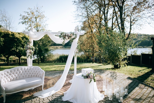 Beautiful wedding ceremony on the shore of the lake and arch with fresh flowers	