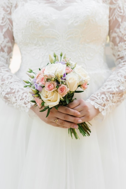 Beautiful wedding colorful bouquet in the hands of the bride Wedding ring on the finger