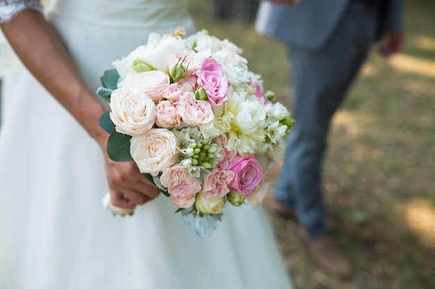 花嫁の手にさまざまな花を持つ美しい結婚式のカラフルな花束。ブライダルサマーブーケ