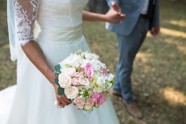 花嫁の手にさまざまな花を持つ美しい結婚式のカラフルな花束。ブライダルサマーブーケ