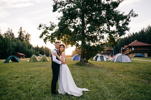 夕暮れ時の屋外を抱いて美しい結婚式のカップル。