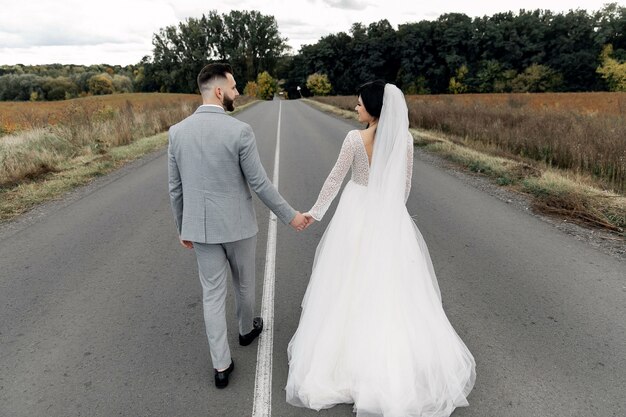 美しい結婚式のカップルは、日没時に市内中心部の道路に抱いています。