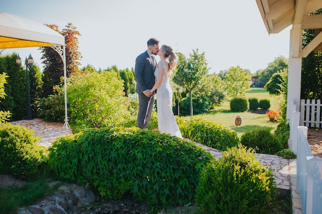 Beautiful wedding couple is kissing standing in the scenic park with white gazebos