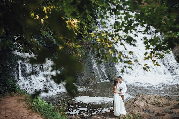 Le belle coppie di nozze si avvicinano alla cascata.