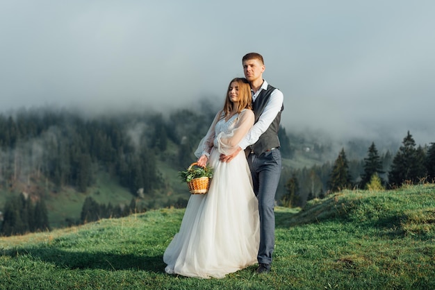 霧の丘の上でポーズをとって美しい結婚式のカップル