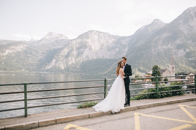 Una bella coppia di sposi cammina vicino a un lago in una fata cittadina austriaca, hallstatt.